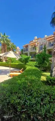 a park with a bench and an umbrella and a building at Veranda sahl hasheesh in Hurghada