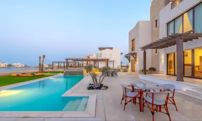 a patio with a pool and tables and chairs at Luxury Stays in Ancient Sands El Gouna in Hurghada