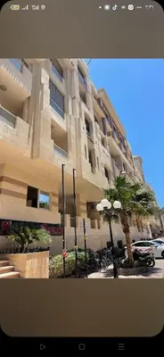 a large building with a palm tree in front of it at Florienza resort in Hurghada