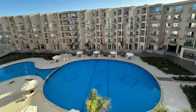 a large apartment building with a large blue pool at princess resort ,arch angilos Hurghada in Hurghada