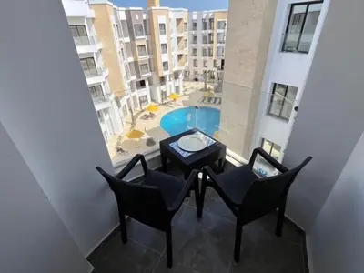 a balcony with chairs and a table and a pool at Aqua Infinity Oasis walking distance to beach, 15 minutes from El Gouna, 15 minutes from central Hurghada in Hurghada