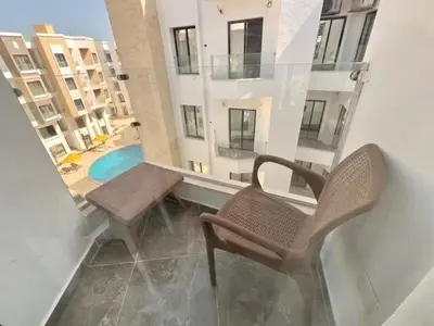 a balcony with a chair and a table and a pool at Aqua Infinity Oasis walking distance to beach, 15 minutes from El Gouna, 15 minutes from central Hurghada in Hurghada