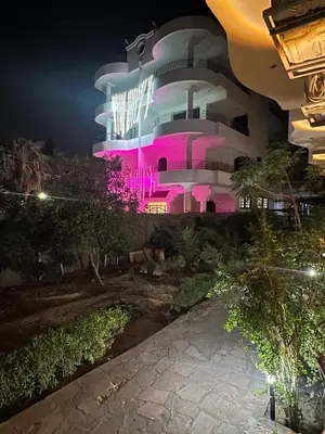 a building with pink lights on it at night at River view house in Luxor