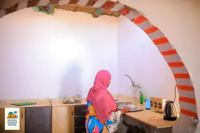 a woman standing in a kitchen preparing food at Heissa Nubian Hostel in Aswân Reservoir Colony