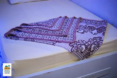a purple and white blanket sitting on top of a bed at Heissa Nubian Hostel in Aswân Reservoir Colony