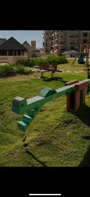 a green park bench sitting in the grass at Modern apartment in Hurghada al dau heights 3314 in Hurghada