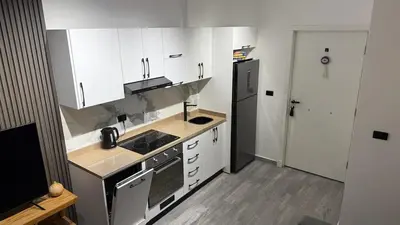 a kitchen with white cabinets and a black refrigerator at Imperial Resort Hurghada in Hurghada
