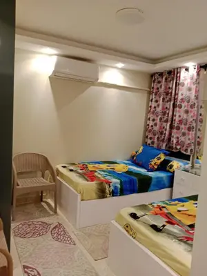a small bedroom with two beds and a chair at Selena Bay Resort in Hurghada