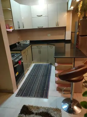 a kitchen with white cabinets and a black counter top at Apartment for rent in Hurghada