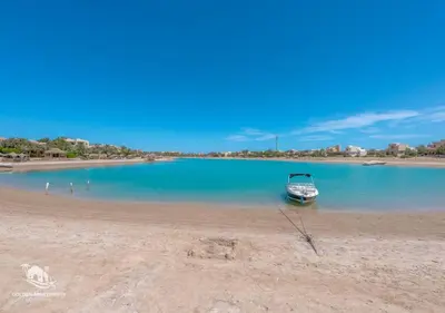 a boat sitting on the shore of a beach at Dreamy 1BR in Italian Compound, Nubia, El Gouna in Hurghada