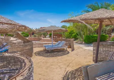a patio with chairs and umbrellas and a bench at Dreamy 1BR in Italian Compound, Nubia, El Gouna in Hurghada