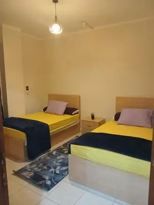 two beds in a room with yellow and purple at Cozy Apartment in Hurghada