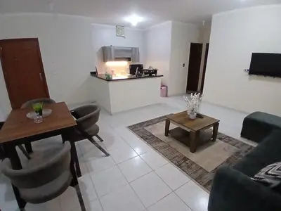 a living room with a table and a kitchen at Cozy Apartment in Hurghada