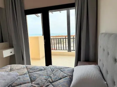 a bedroom with a bed and a view of the ocean at Luxury hotel apartment 2rooms with triple sea view in Hurghada