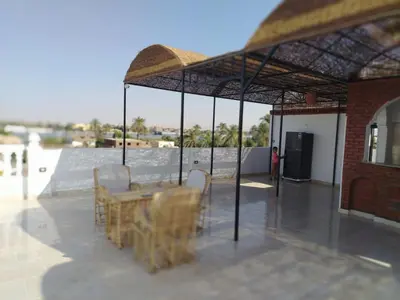 a patio with a table and chairs under a pavilion at Mena Palace Nile View in Luxor