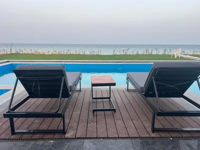 two chairs and a table on a deck next to a pool at Villa KUBA luxury in Hurghada