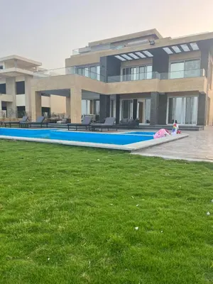 a building with a large swimming pool in front of a yard at Villa KUBA luxury in Hurghada