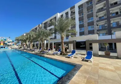 a swimming pool with blue chairs and a building at Fanadir Bay apartment in Hurghada