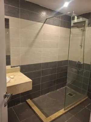 a bathroom with a glass shower with a sink at Fanadir Bay apartment in Hurghada