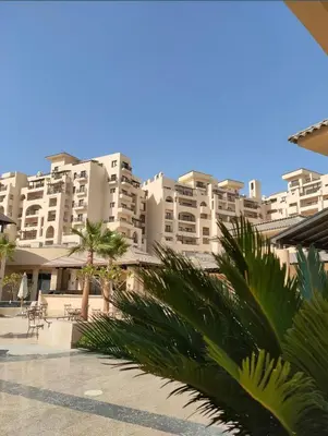 a large apartment building with palm trees in the foreground at Studio in Dow Heights Compound in Hurghada