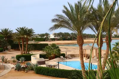 a resort with a swimming pool and palm trees at Spacious 1bd on the Beach - White Villas, El Gouna in Hurghada