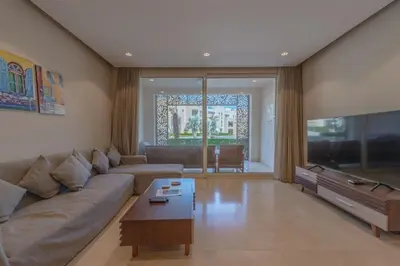 a living room with a couch and a flat screen tv at Mangroovy- 1br GF Waterfront Glitzy direct pool in Hurghada