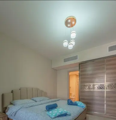 a bedroom with a bed with blue pillows on it at Mangroovy- 1br GF Waterfront Glitzy direct pool in Hurghada