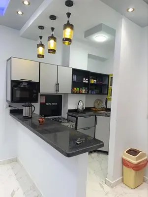 a kitchen with white cabinets and a black counter top at براديس الاحياء in Hurghada