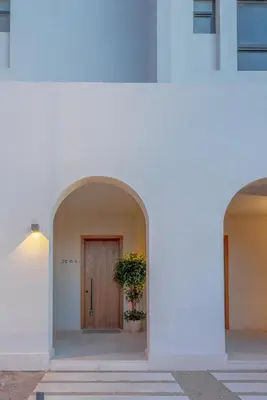 a white building with a door and a potted plant at Chic 1 BR with private jacuzzi in Banī Ghālib