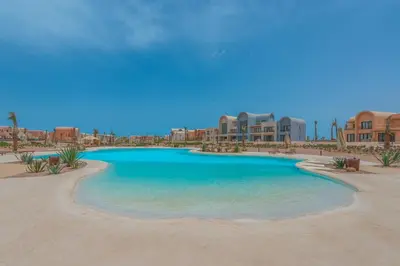 a swimming pool in the middle of a beach with buildings at Chic 1 BR with private jacuzzi in Banī Ghālib