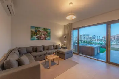 a living room with a couch and a large window at Chic 1 BR with private jacuzzi in Banī Ghālib