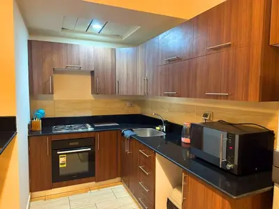 a kitchen with wooden cabinets and a microwave at Coral Aldau Heights one bedroom apartment in hurghada in Hurghada
