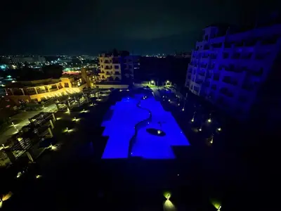a large pool with blue lights in a city at night at Coral Aldau Heights one bedroom apartment in hurghada in Hurghada