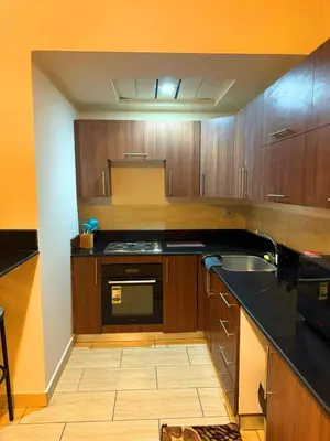 a kitchen with wooden cabinets and a black counter top at Coral Aldau Heights one bedroom apartment in hurghada in Hurghada