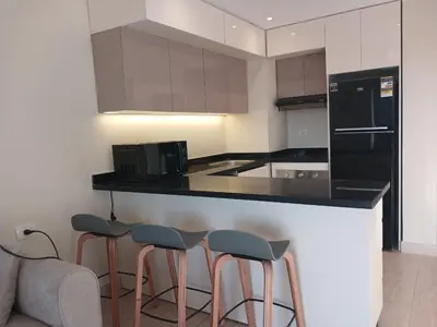 a kitchen with three bar stools and a black refrigerator at Crystal Aldau Heights one bedroom apartment in Hurghada in Hurghada