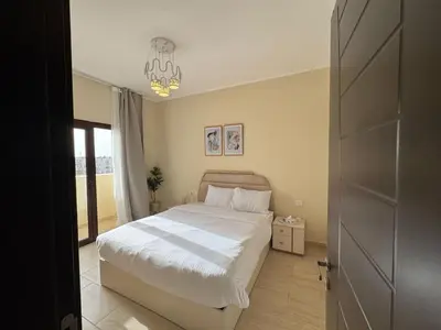 a bedroom with a white bed and a chandelier at Paradise Aldau Heights one bedroom apartment in Hurghada in Hurghada