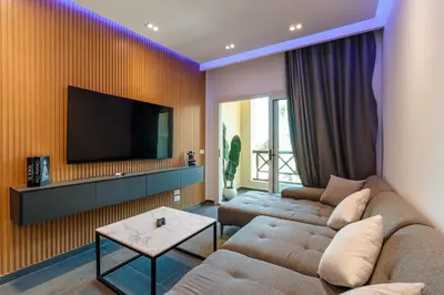 a living room with a couch and a tv on a wall at Al Saraya Sahl Hasheesh by Peaks One Bedroom Apartment with Pool View C201 in Hurghada