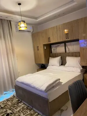 a bedroom with a large bed with wooden cabinets at The Modern Nest Magawish in Hurghada