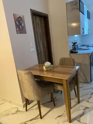 a wooden table and a chair in a room at The Modern Nest Magawish in Hurghada