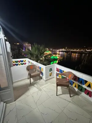a balcony with two chairs and a fence at night at Anno ka in Jazīrat Aswān