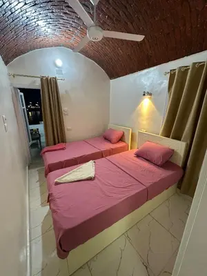 two beds in a room with pink sheets at Anno ka in Jazīrat Aswān