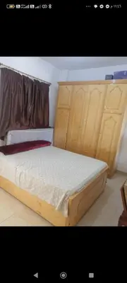 a bed in a room with wooden cabinets at Luxor Egypt in Al Baghdādī