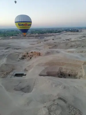 a hot air balloon flying over a desert at House of peace in Al Aqālitah