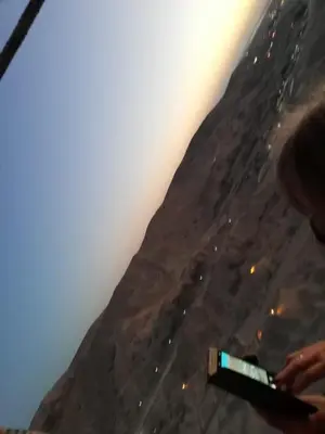 a person holding a bottle in front of a mountain at House of peace in Al Aqālitah