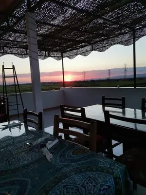 a patio with a table and chairs and the sunset at House of peace in Al Aqālitah