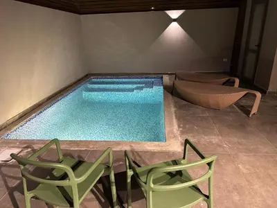 a swimming pool with two green chairs and a table and chairs at Modern 2BR Villa With Private Pool In Bali In ElGouna in Hurghada