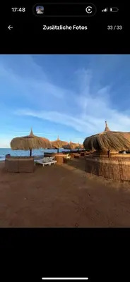 a group of straw umbrellas on a beach at Luxus Apartment in Hurghada