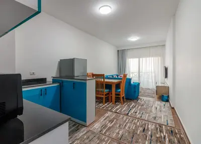 a kitchen and dining room with blue cabinets and a table at Al Saraya Sahl Hasheesh by Peaks One Bedroom Apartment With Pool View C304 in Hurghada