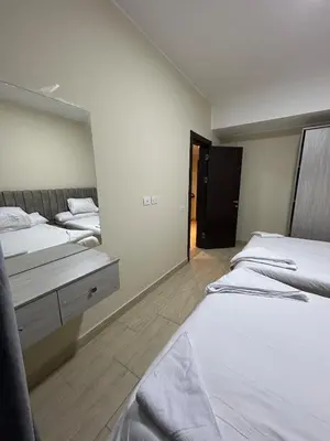 a hotel room with three beds and a mirror at 1-Bedroom Aldau Heights in Hurghada