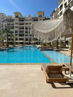 a swimming pool in front of a large building at 1-Bedroom Aldau Heights in Hurghada